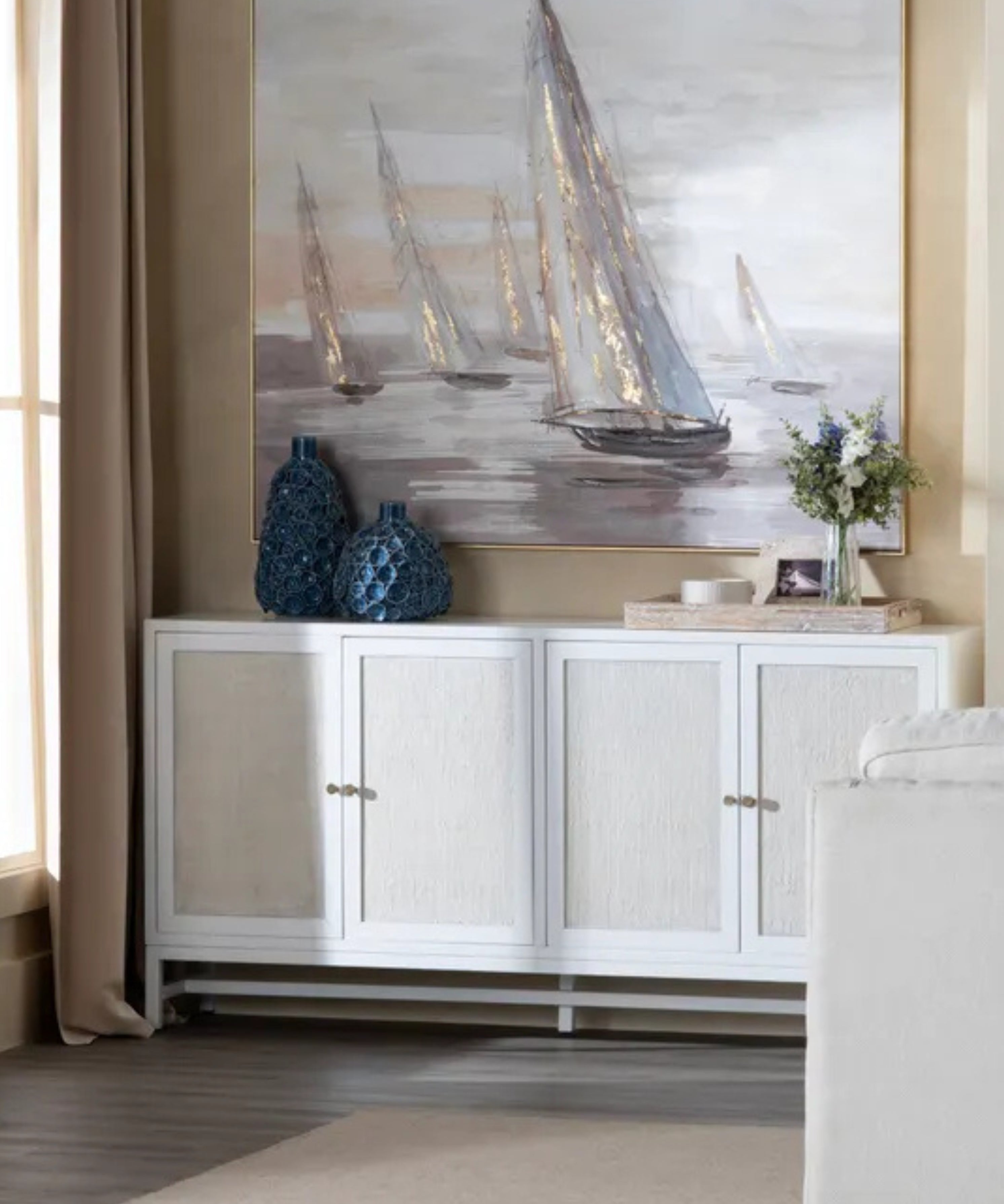 Living room with a white cabinet, decorative vases, and a large painting of sailboats.