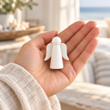Small white pocket angel resting in an open hand