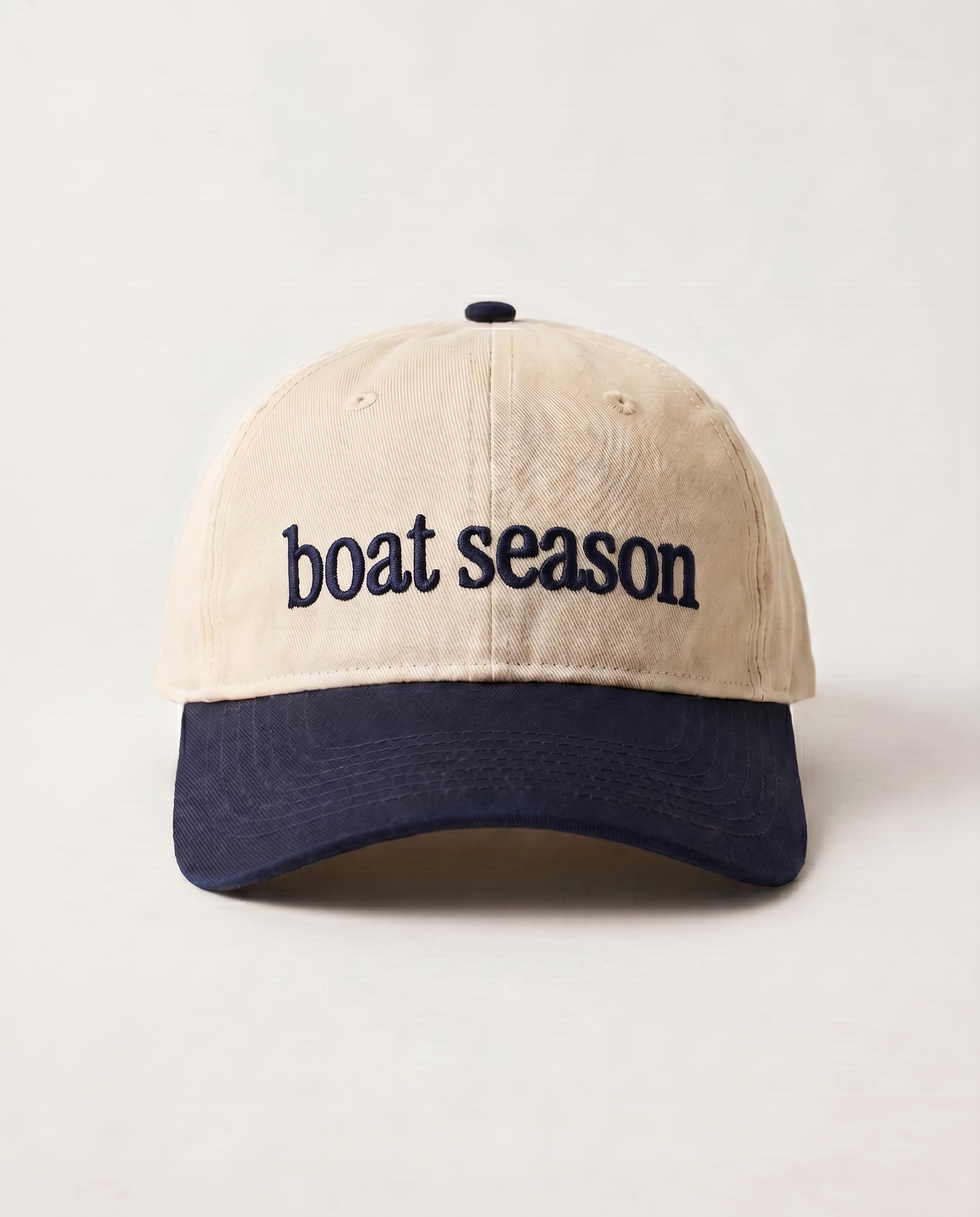 Beige and navy cap with 'boat season' text on a light gray background