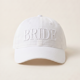 White cap with 'BRIDE' embroidery on a beige background