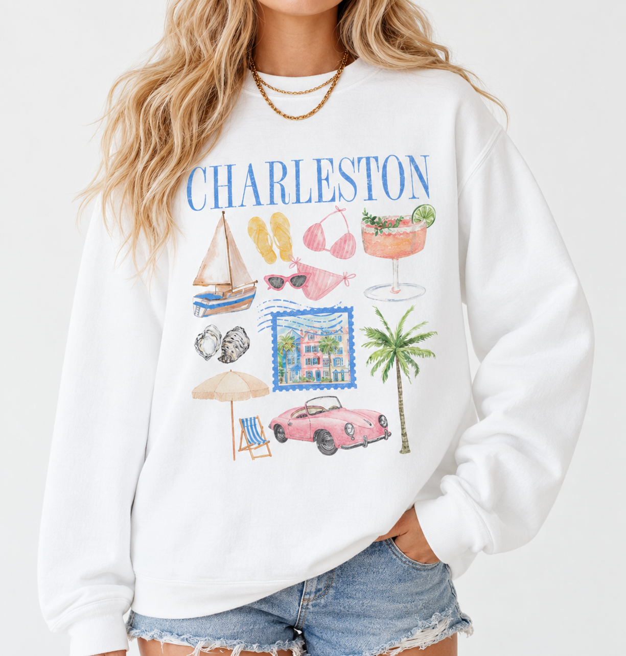 Woman wearing a white Charleston graphic sweatshirt featuring colorful coastal illustrations, blue lettering, and a relaxed fit.