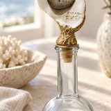 Close-up of the oyster shell and gold-tone stopper on a clear glass bottle.