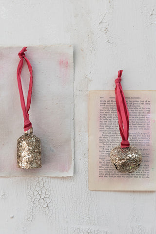 Decorative bells with red ribbons on vintage books against a textured white background