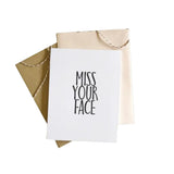 Greeting card with 'Miss Your Face' text inside a beige envelope on a white background