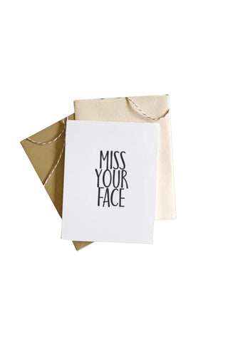 Greeting card with 'Miss Your Face' text inside a beige envelope on a white background