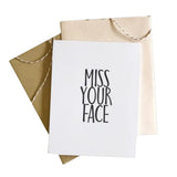 Greeting card with 'Miss Your Face' text and beige envelope on white background