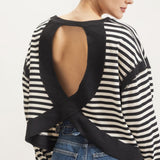 Back view of women's black and cream striped long sleeve top featuring a dramatic open-back design with crisscross fabric detailing.