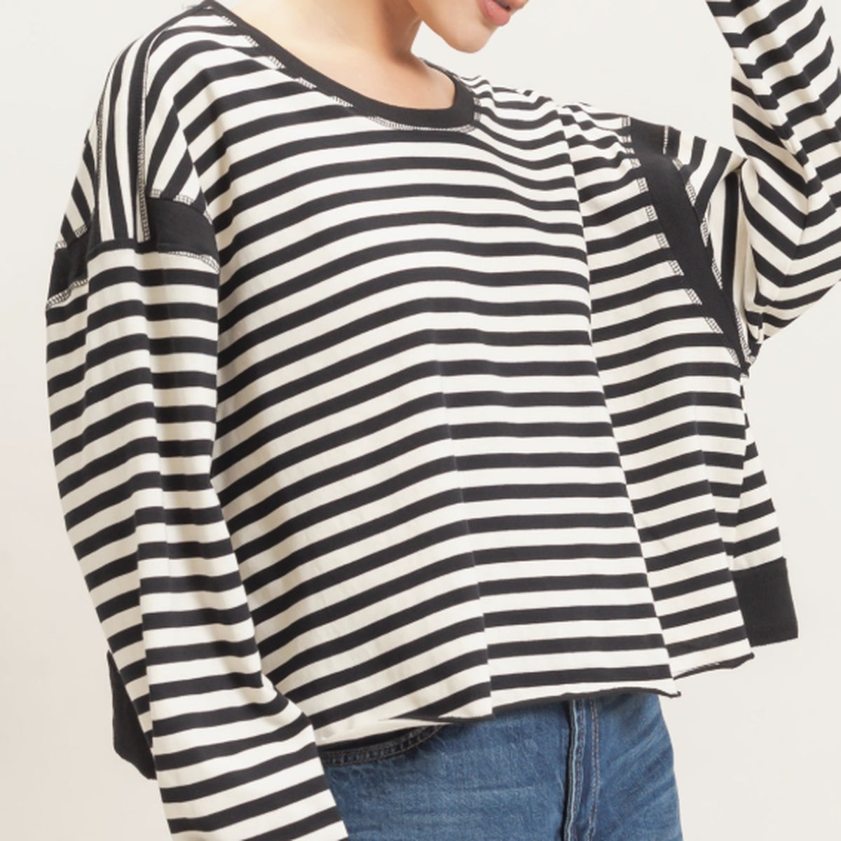 Women's black and cream striped cropped long sleeve top with a relaxed silhouette, dropped shoulders, and contrasting ribbed cuffs.