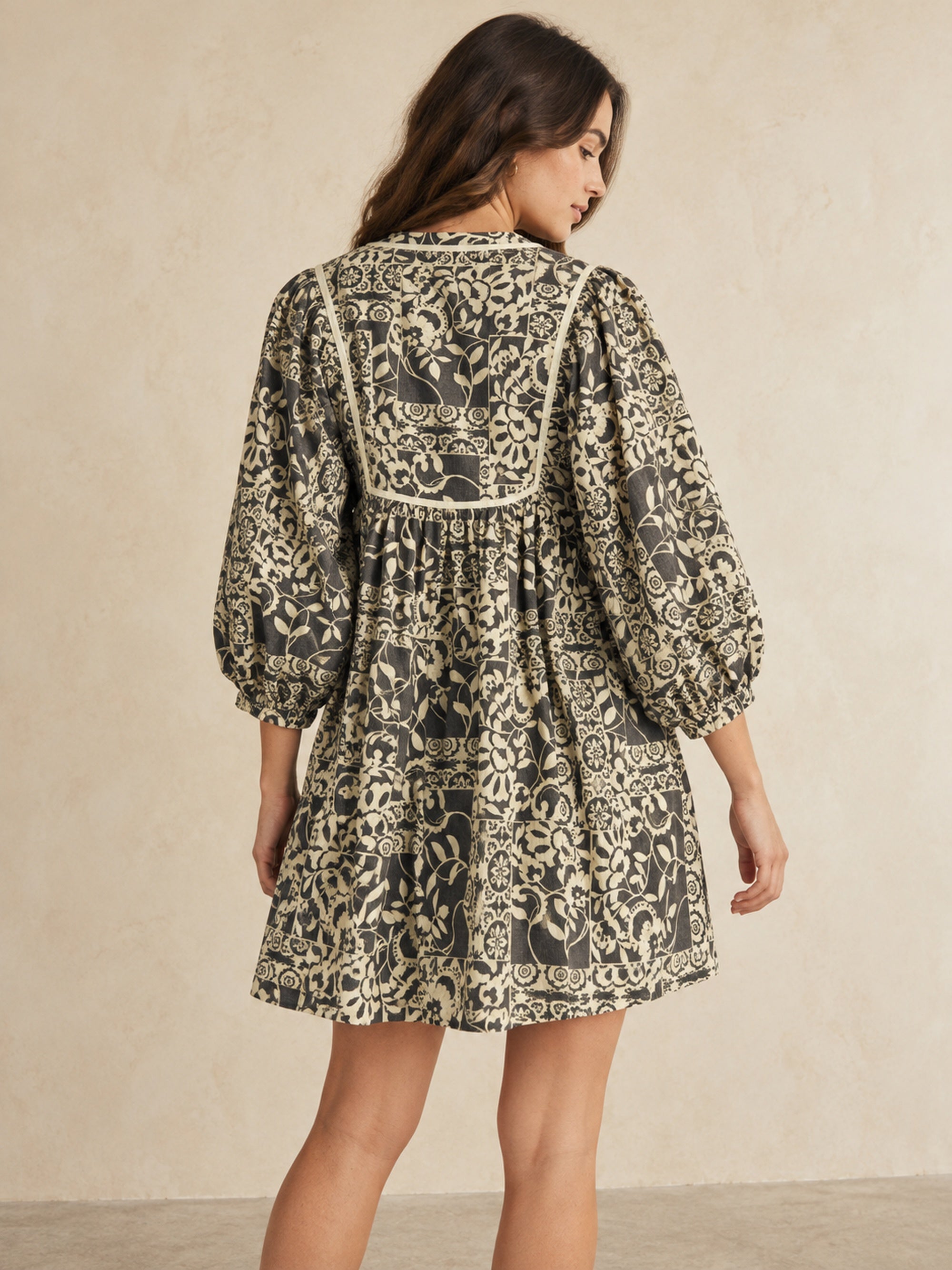 Back view of charcoal and cream botanical cotton peasant dress showing contrasting yoke trim and gathered silhouette.