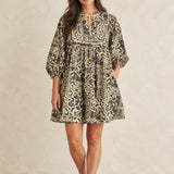 Front view of charcoal and cream floral and leaf print cotton peasant dress with tie neck and three-quarter puff sleeves.