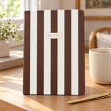 Brown and cream striped notebook styled on a desk with a mug and gold-tone pen