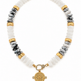 Coastal Medallion Beaded Necklace featuring white acrylic rondelle beads, marbled gray accents, gold-tone spacers, and an ornate medallion pendant, 17 inches long.