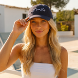 Woman wearing a navy blue cap with 'east coast' text outdoors.