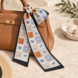 Black and orange equestrian patchwork twilly scarf tied around a tan handbag.
