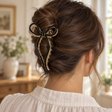 Black acrylic inlay gold-tone bow claw hair clip worn in a brunette updo