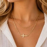 Layered gold sideways cross necklace worn by model