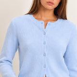Women's light blue button-front knit cardigan with crew neckline and ribbed trim, styled with blue jeans, front view.