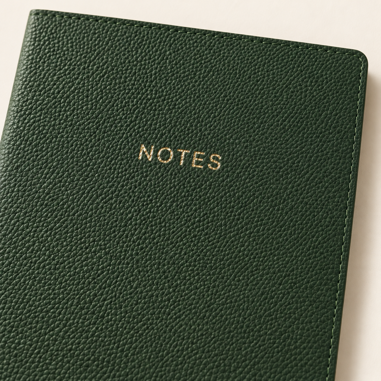 Close-up of the green journal's pebbled vegan leather cover, gold NOTES lettering, and stitched edge.