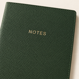 Close-up of the green journal's pebbled vegan leather cover, gold NOTES lettering, and stitched edge.