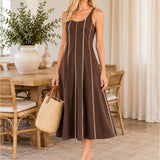 Full-length model wearing chocolate brown contrast piping midi dress in coastal interior