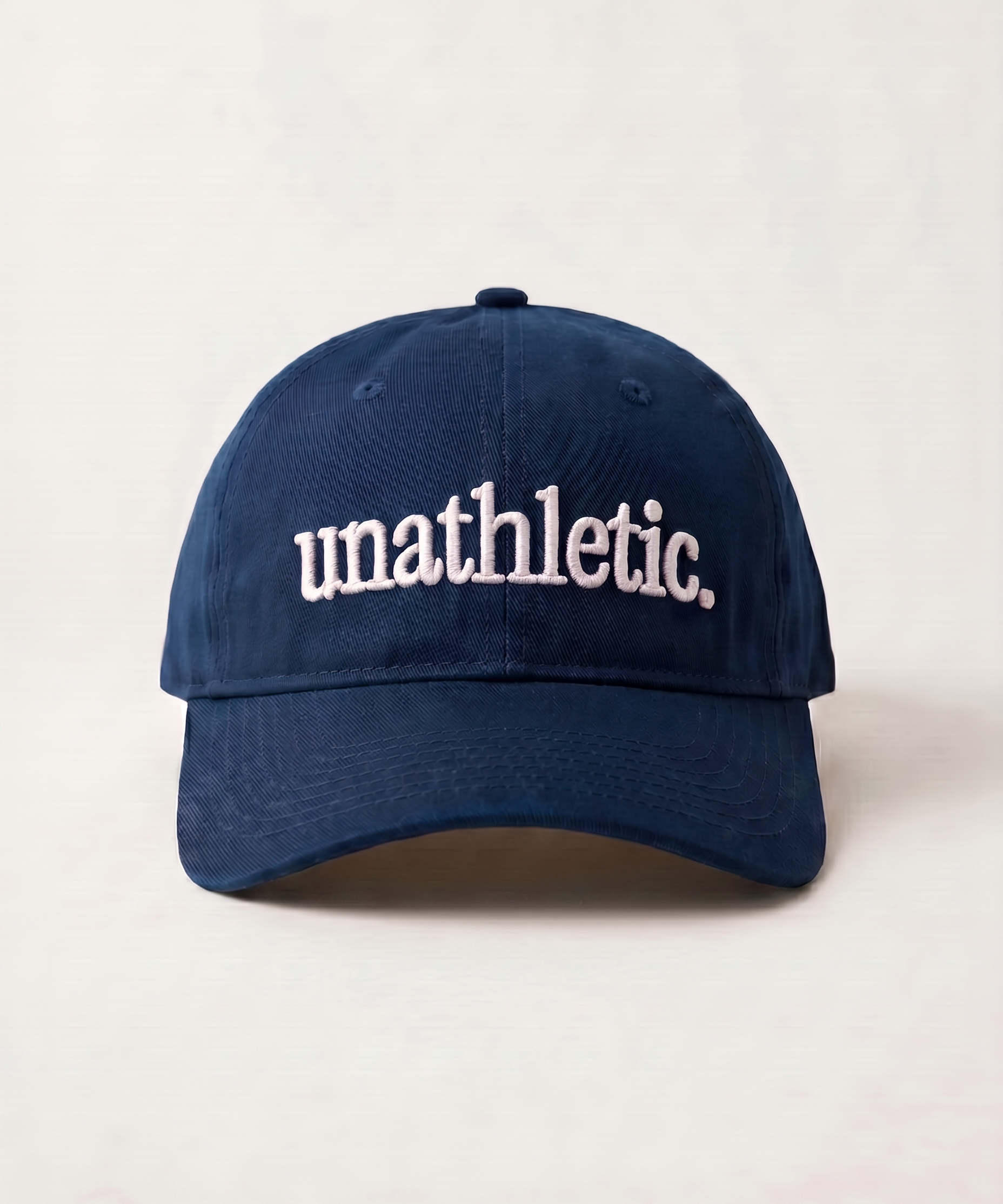 Navy blue cap with 'unathletic' text on a light beige background